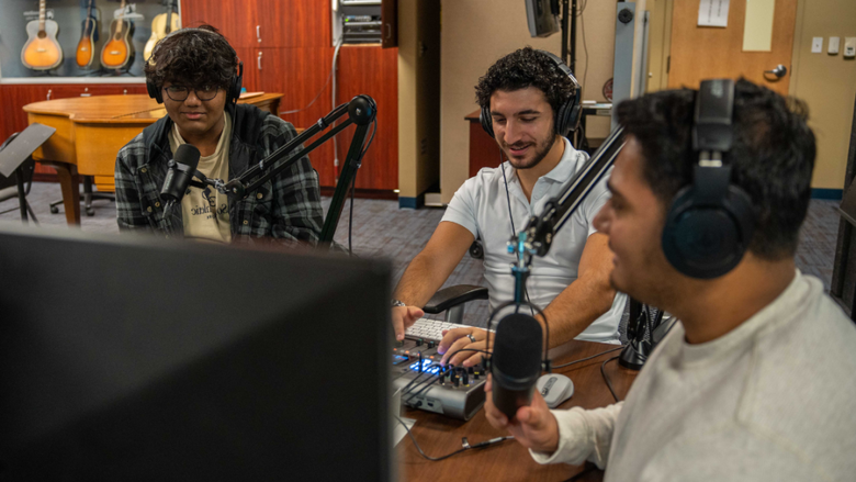 3 male students sitting in a podcasting booth 